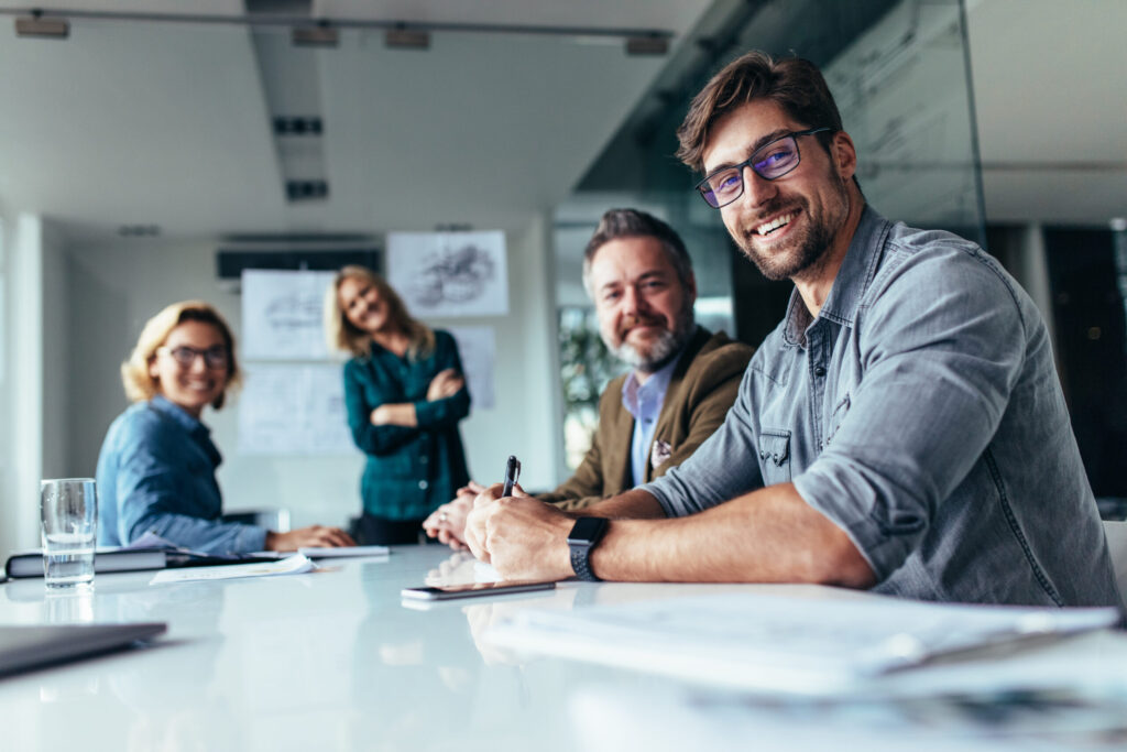 Group of workers looking at a camera while sitting at a desk.
